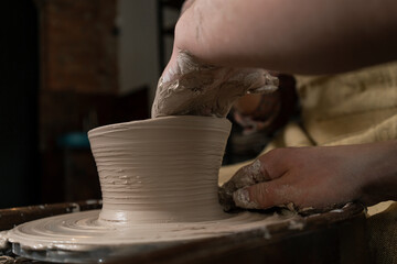 pottery, workshop, ceramics art concept - closeup on male hands sculpt new utensil with a tools and water, man's fingers work with potter wheel and raw fireclay, front close view