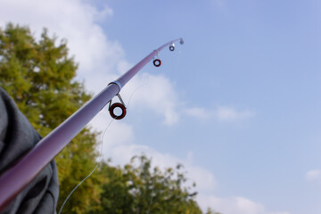 person fishing with a fishing rod and at the lake