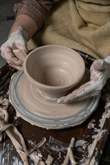pottery, workshop, ceramics art concept - closeup on male hands sculpt new utensil with a tools and water, man's fingers work with potter wheel and raw fireclay, front close view