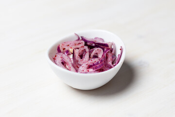 Red onion with sumac, salt and lemon juice in white bowl