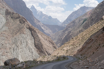 Narrow mountain valley between steep gray rocky cliffs in Ayni, Tajikistan's Fann Mountains.