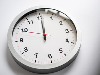 Close up of a ticking clock on white background, pointing a few minutes past midnight, copyspace, window reflection