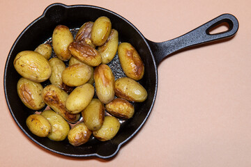 British roasted baby potatoes in cast iron pan. Browned and cooked potoates on pan. Sunday roast. Festive meal.