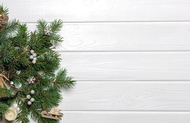 Fototapeta na wymiar Pine tree branches with New Year ornaments on white wooden background. Copy space