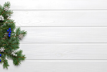 Pine branches, snowflake ornaments and blue berries on white wooden background. Copy space