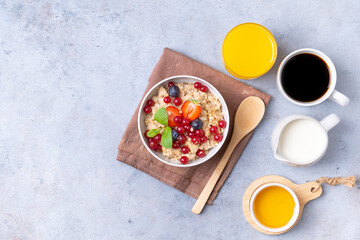 Healthy breakfast set on grey background. The concept of delicious and healthy food. Mix nuts, honey, berries, orange jus, pancake and milk. Top view, copy space.