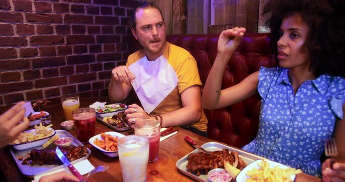 Group of multi-ethnic friends laughing and enjoying meal in restaurant