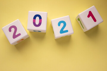 Scattered cubes with colorful numbers 2021 on yellow background. New year, calendar