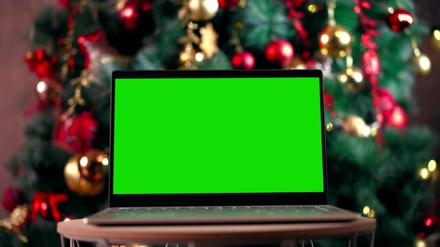 Modern chroma key green screen laptop computer against the background of the christmas tree - remote work, technology concept. Close-up. High quality 4k footage