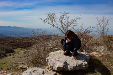 Young woman squats on a rock. natural landscape