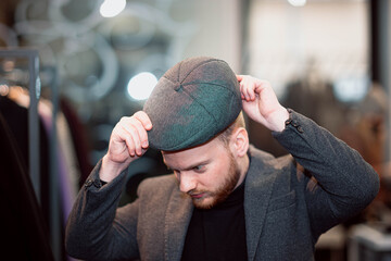 man in business clothes chooses a classic cap in a store.