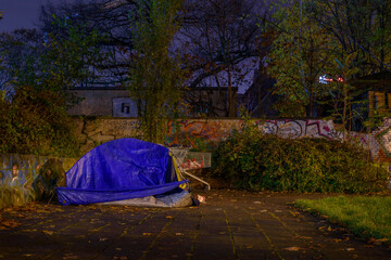 Tent of a homeless person in the city at night, shopping cart and a tent of a homeless person at night, rainy weather