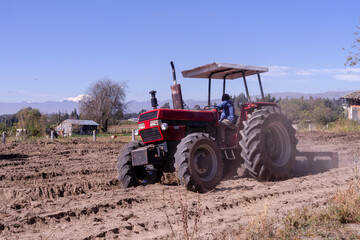 Fototapeta premium Tractor in a field with a mountain view