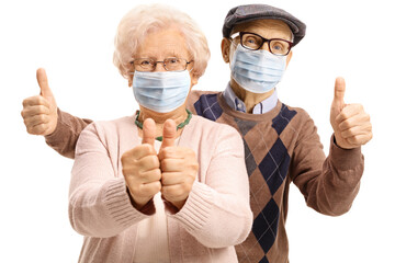 Elderly man and woman with protective face masks showing thumbs up