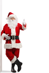 Santa claus leaning on a wall and gesturing a thumb up sign