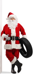 Full length portrait of santa claus leaning on a wall and holding a car tire