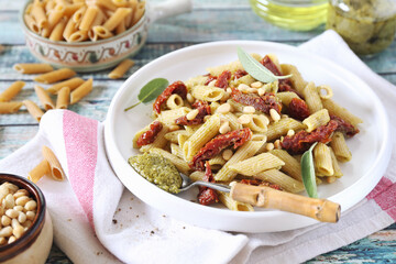 Whole wheat penne pasta with pesto sauce and sun dried tomatoes and pine nut