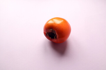 One ripe persimmon fruit on a pastel background, close-up, side view, space for text