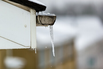 Dripping icicles on a house roof in winter