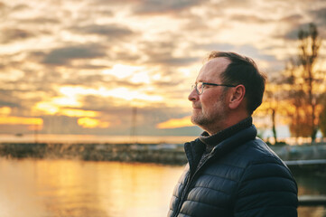 Outdoor portrait of middle age man enjoying nice sunset over lake