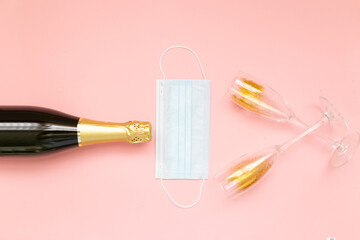Bottle of champagne face mask and glasses with gold glitter on pink background. Party decor. Christmas, birthday or wedding concept. Flat lay. Festive, drink. New year 2021 celebration. 2