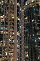 Cluster of illuminated high-rise residential towers in the Dubai Marina district of Dubai, United Arab Emirates, stands against a dark January night sky. Countless lit windows form a pattern of light 