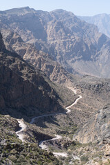 Craggy cliffs tower over the rugged canyons of Oman on 7 February 2020, with sheer rock walls and jagged ridges creating dramatic patterns of light and shadow across the desert mountainside.