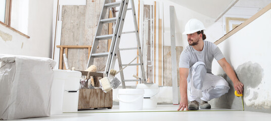 construction worker plasterer man measuring wall with measure tape in building site of home...