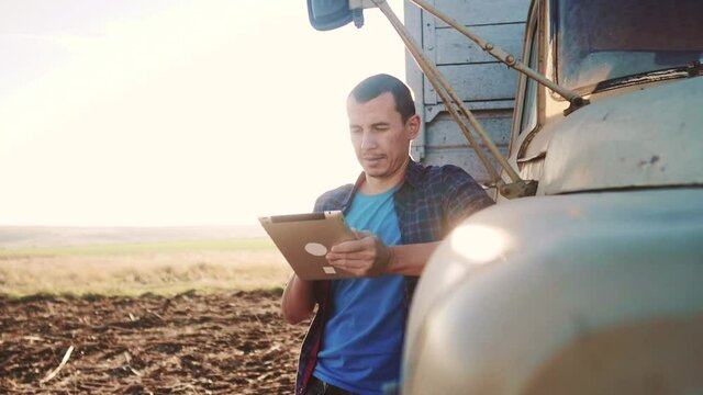 agriculture. farmer driver with digital tablet works next to the car. agriculture business a farming concept. farmer looking farm at work plan on digital tablet