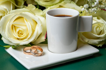 bouquet of pink and white roses, a cup of coffee and wedding rings