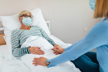 Obraz premium Beautiful middle age woman spending some time with her mother in hospital or nursing center. Senior woman lying in bed.