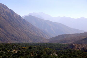 Fototapeta na wymiar Perspective view of the mountain range, above the palm grove, Nakhal, Al Batinah Region of Oman