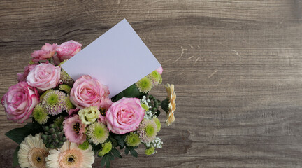 bouquet of roses on wooden background with white card  - copy space