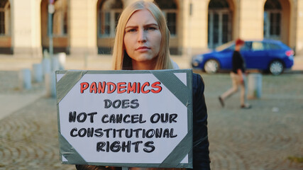 Protest walk declaring that pandemic does not cancel human constitutional rights. Woman with steamer walking on the street.