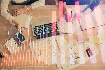 Double exposure of woman hands working on computer and forex graph hologram drawing. Top View. Financial analysis concept.