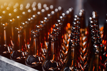 Glass beer bottles of brown color on the conveyor line of beer bottling close up
