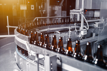 Glass beer bottles of brown color on the conveyor line of beer bottling close up