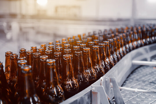 Glass beer bottles of brown color on the conveyor line of beer bottling close up