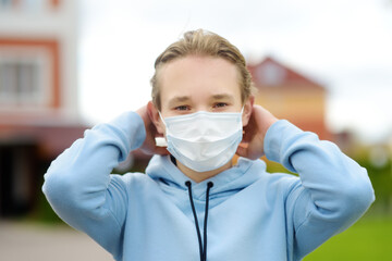 Obraz na płótnie Canvas A teenage boy put on a face mask because the second wave of the covid-19 epidemic began. Lockdown. The mask is the new standard for protection and prevention during a coronavirus or flu outbreak.