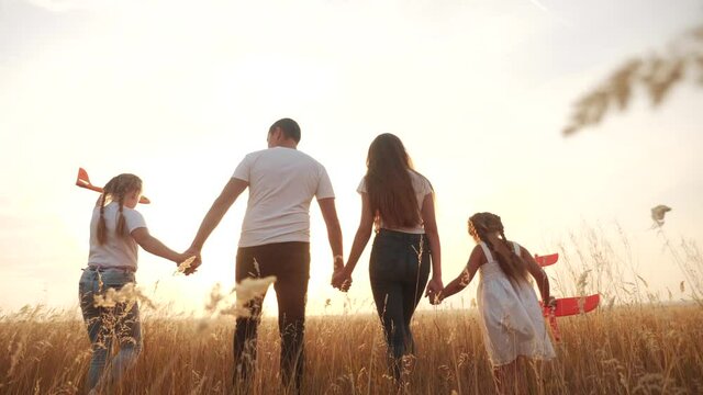people in the park. happy family silhouette walk with a toy plane. mom dad and daughters walk holding hands in park. happy family kid dream concept airplane. parents and child walking back silhouette