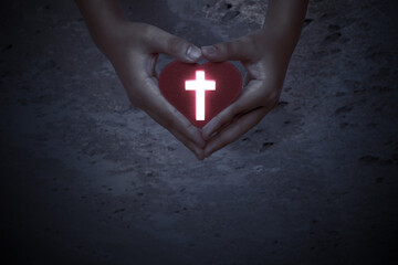Human hands showing red heart with Christian cross