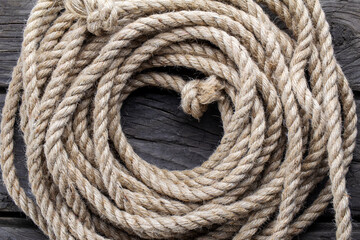 Ship rope in shape circle on dark wooden background. Wooden background from an old board with hemp rope.  Frame of rope. Top view.