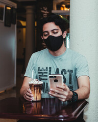 young man in a coffee shop enjoying a couple of drinks using technology
