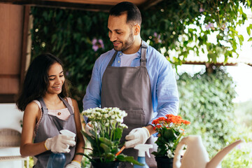 Father and daughter watering potted plants at home