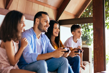 Latin family enjoying the day together at home playing video games on the couch