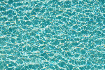 Fototapeta na wymiar Top view of beautiful swimming pool with clear water and sunlight reflection on the surface in blue and turquoise color in the morning 