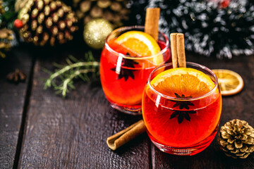 Mulled red wine with spices and Christmas fruits on a rustic wooden table with Christmas colors and lights. Traditional hot drink at Christmas time