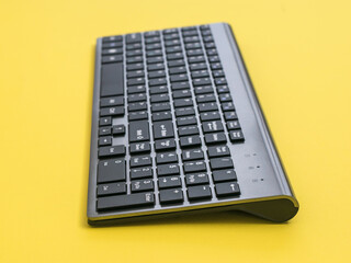 Modern wireless keyboard on a yellow background.
