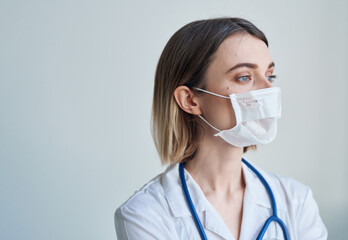 Woman doctor in a medical mask with a stethoscope around her neck