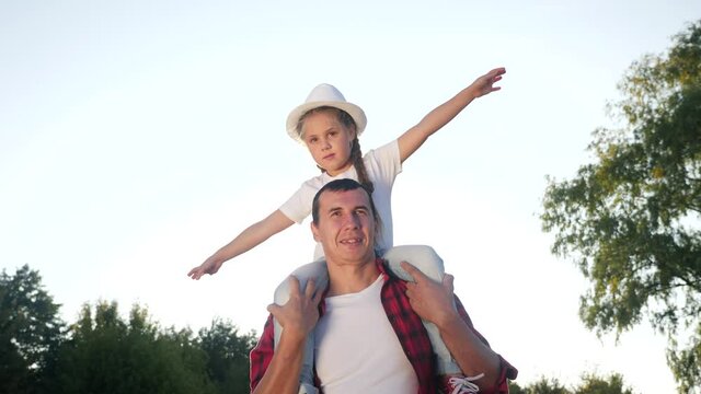 happy family silhouette kid dream concept. daughter kid superhero sitting on his father man neck depicts a dream flight of an airplane playing a pilot. happy family father and kid daughter silhouette